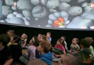 Dzieci oglądają film w mobilnym planetarium.