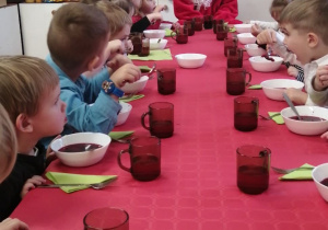 Dzieci jedzą obiad z Mikołajem.