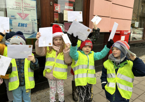 Dzieci trzymają listy pod pocztą.