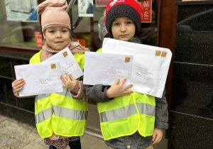 Dzieci trzymają listy pod pocztą.