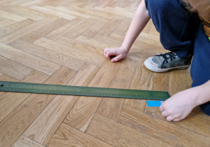 Dziecko mierzy linijką pasek.
