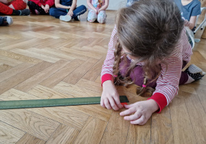 Dziecko mierzy linijką pasek.