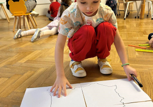 Chłopiec składa kontur mapy Polski.