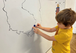 Dziecko przykleja podpis na mapie Polski.