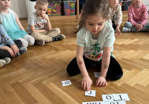 Dziewczynka układa z liter wyraz.