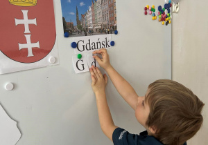 Dziecko przyczepia literki do tablicy.