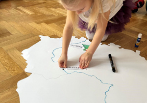 Dziecko przykleja podpis na mapie Polski.