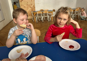 Dzieci jedzą tosty.