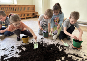 Dzieci sypią ziemię do doniczek.