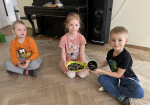 Dzieci pokazują doniczki z nasionami.