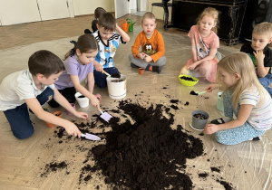 Dzieci sypią ziemię do doniczek.