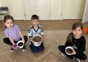 Dzieci pokazują doniczki z nasionami.