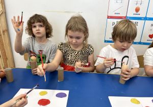 Dzieci malują farbami jajka.