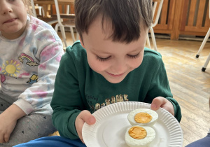 Dziecko ogląda i wącha jajko.