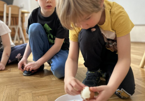 Dziecko obiera ze skorupki jajko.