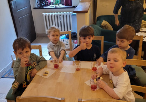 Dzieci jedzą ciasteczka i piją soczek.