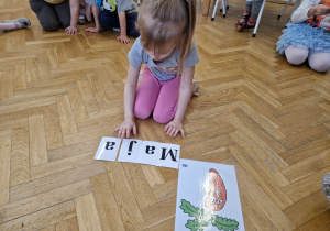 Dziewczynka układa z liter imię Marchewki.