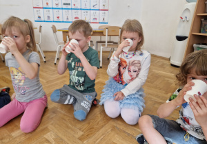 Dzieci częstują się soczkiem marchewkowym.