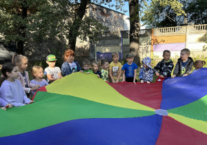 Dzieci z grupy trzeciej i czwartej podrzucają chustę animacyjną.