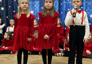 Dwie dziewczynki i chłopiec śpiewają piosenkę ,,Mikołajkowa piosenka".