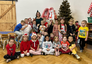 Zdjęcie grupowe - grupa czwarta. Część dzieci stoi, druga część dzieci siedzi. Na środku całej grupy stoi mama chłopca. Wszyscy na zdjęciu uśmiechają się.