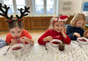 Dziewczynki z grupy czwartej jedzą obiad wigilijny - barszczyk czerwony.