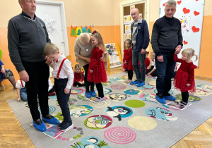 Dziadkowie tańczą z wnukami na rozłożonych gazetach.