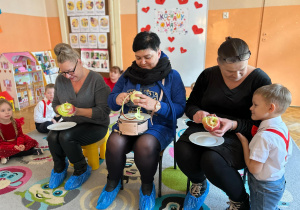 Babcie siedzą na krzesłach i obierają jabłka.