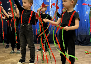 Chłopcy trzymają serduszka na wykałaczkach i machają nimi.