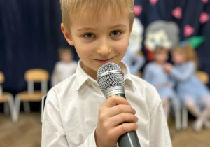 Chłopiec trzyma mikrofon i mówi wiersz.