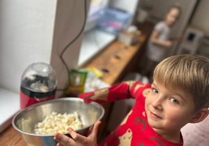 Chłopiec trzyma miskę z popcornem.