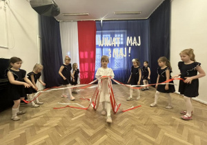Zdjęcie grupowe- dziewczynki stoją w małej grupie, jedna z dziewczynek trzyma białe i czerwone wstążki.