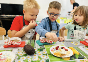 Chłopcy próbują jadalnych ozdób, którymi ozdabiają czekoladki.