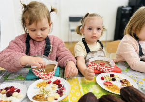 Dwie dziewczynki ozdabia czekoladki w kształcie serca.