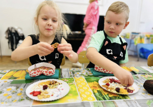 Chłopiec i dziewczynka ozdabiają czekoladę w kształcie serca.