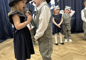Dziewczynka i chłopiec trzymają mikrofon i mówią wiersz.