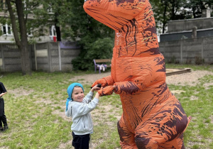 Chłopiec tańczy z dinozaurem.