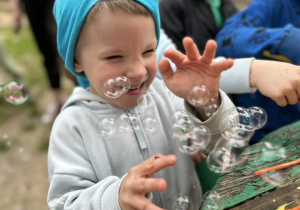 Chłopiec bawi się bańkami mydlanymi.
