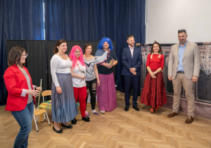 Rodzice stoją w półkolu. W tle gra piosenka finałowa o rodzinie.