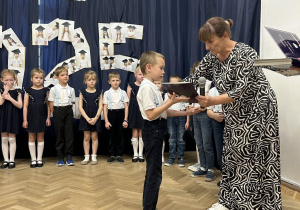 Chłopiec odbiera dyplom od Pani Dyrektor.