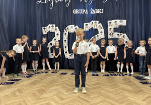Chłopiec trzyma mikrofon i mówi wierszyk.