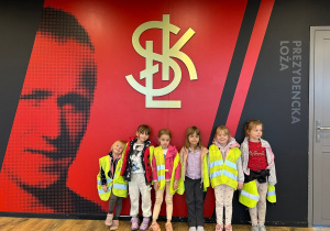 Dzieci stoją na tle symbolu ŁKS.