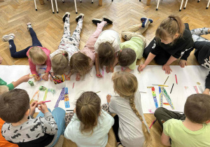 Dzieci kolorują literki na transparencie.