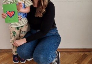 Wspólne zdjęcie pracownika przedszkola z dzieckiem. Dziecko wręczyło laurkę Pani.