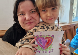 Wspólne zdjęcie pracownika przedszkola z dzieckiem. Dziecko wręczyło laurkę Pani.