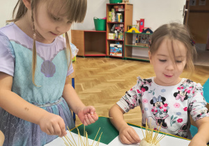 Dzieci wkładają w kulki z masy solnej makaron.