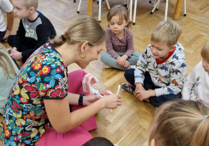Dzieci patrzą jak prawidłowo myć zęby. Pani pokazuje jak prawidłowo myć zęby na modelu szczęki.