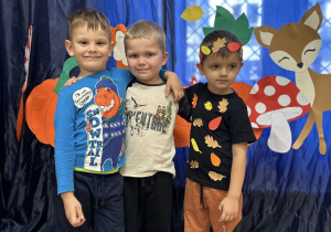 Zdjęcie grupowe - chłopcy z grupy III. Chłopcy w strojach jesiennych stoją na tle dekoracji.