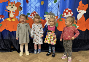 Dzieci z grupy I stoją w strojach jesiennych na tle dekoracji.