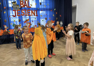 Dzieci z grupy IV stoją w małych kółeczkach i klaszczą.